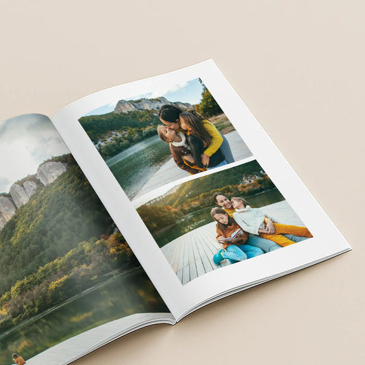 Softcover photo book open to photos of a mother and two daughters kissing and sitting together on a lakeside dock surrounded by autumn cliffs.