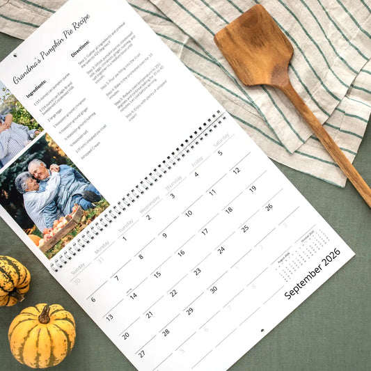 September 2026 wall calendar page featuring Grandma's Pumpkin Pie recipe and a photo of an older couple at an apple orchard, above the date grid.