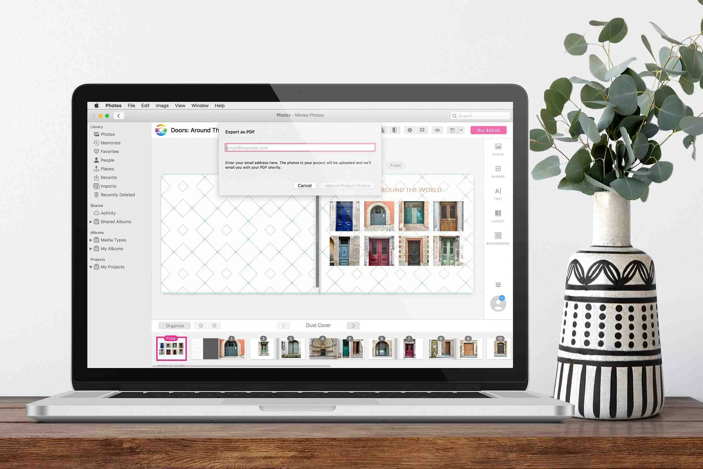 Laptop displaying photo book editor interface with page layout and export to PDF dialog window open, positioned on wooden desk with decorative plant.