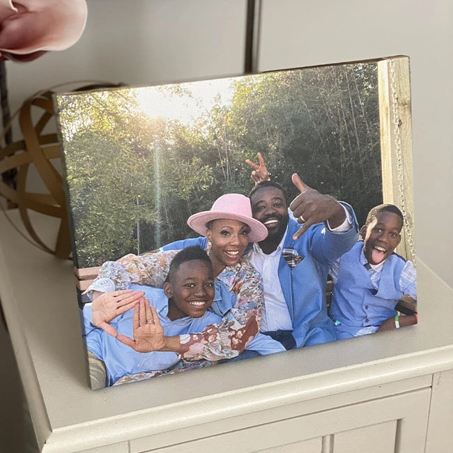 Canvas print of a joyful family of four laughing and posing playfully outdoors in matching blue outfits.