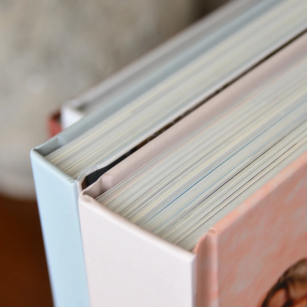 Detail shot of layflat photo books with pastel covers, highlighting thick, premium pages and durable binding construction.