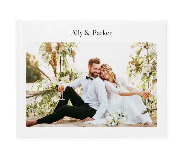 Layflat wedding photo book cover with minimalist white design, couple portrait centered, and names displayed at top.
