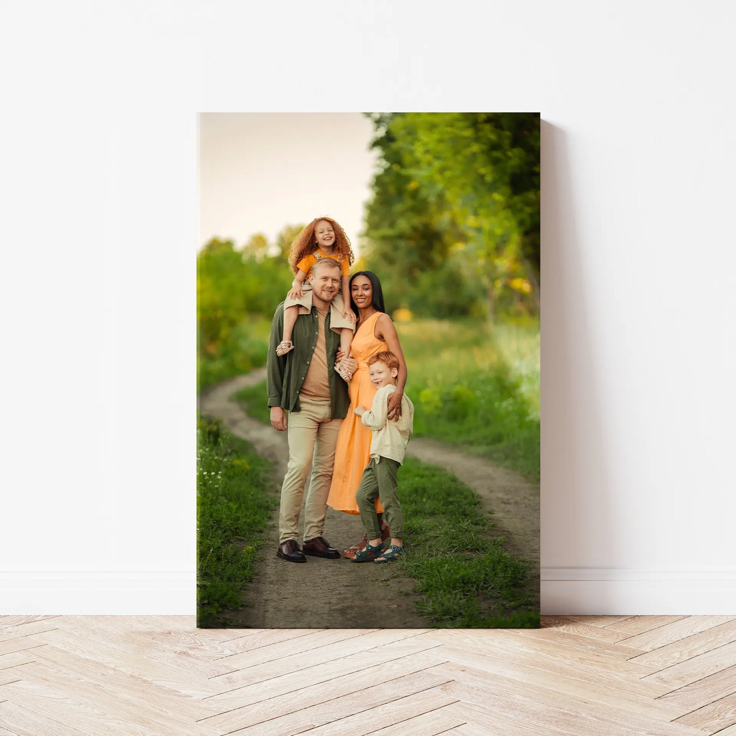 Acrylic wall print showing a family of four standing on a dirt path in a green outdoor setting, with two adults and two children smiling together.