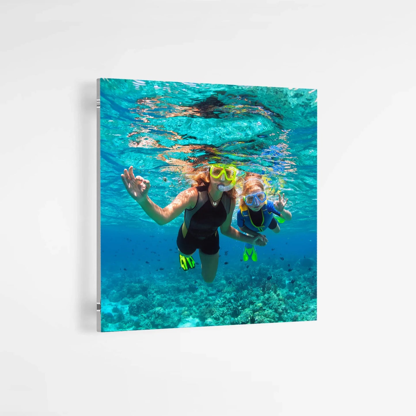 Acrylic wall print showing two people snorkeling underwater wearing masks and fins above a coral reef in clear blue ocean water.