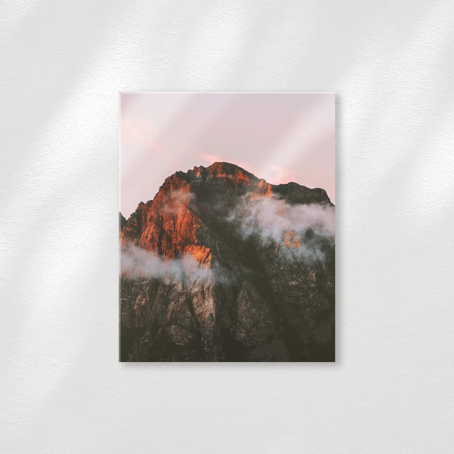 Acrylic print featuring a mountain peak with warm sunset light and drifting clouds, displayed on a neutral wall with a matte finish.