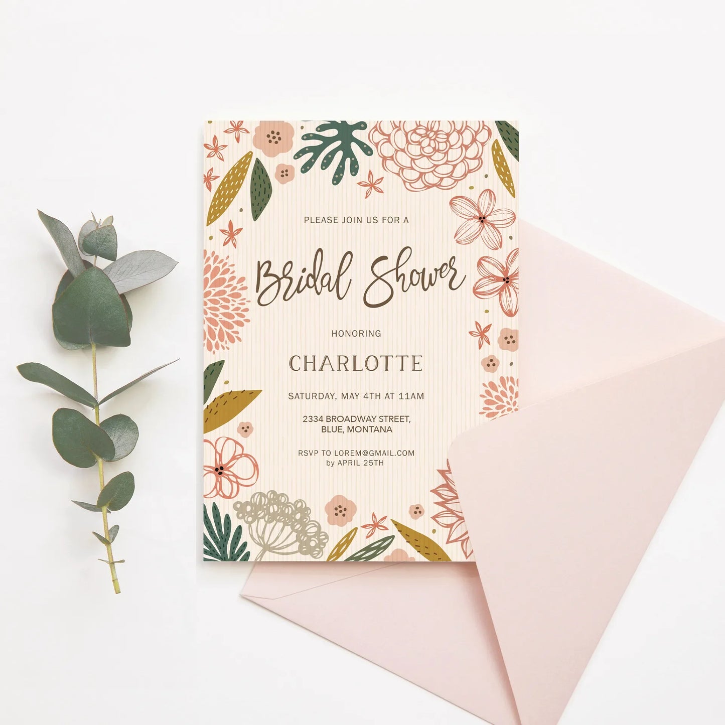 Flat floral bridal shower invitation with illustrated flowers and event details, paired with blush envelope on white surface.