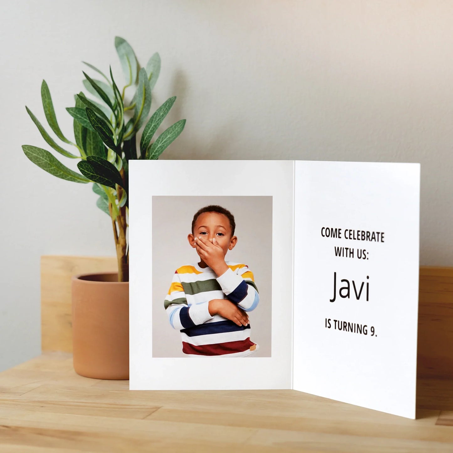 Open folded birthday invitation card with child portrait on left panel and text reading “Javi is turning 9” on right.