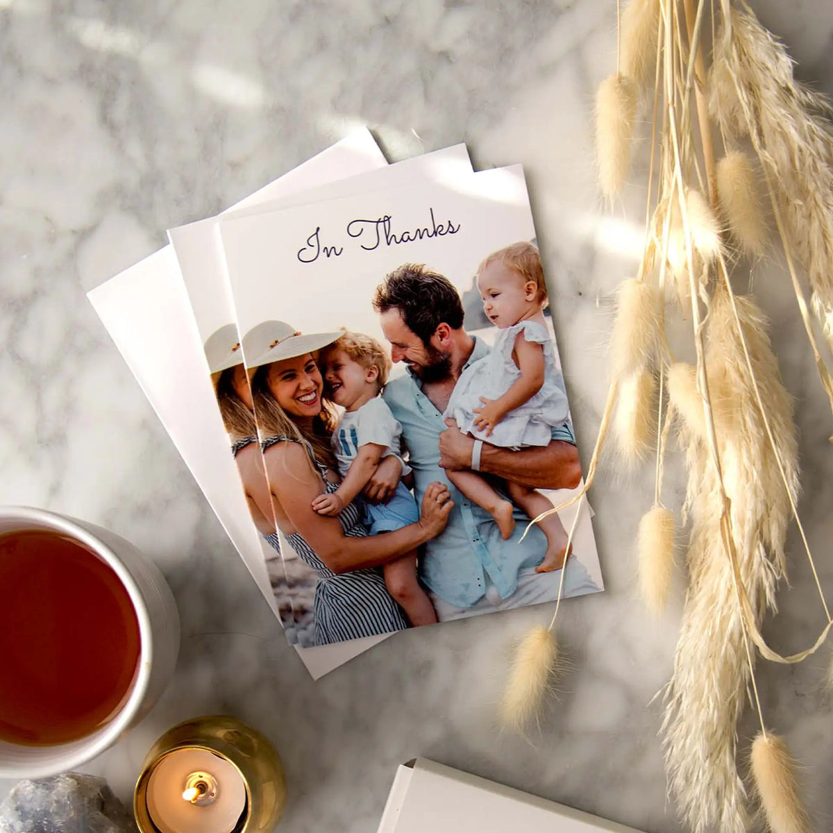Folded thank you cards reading 'In Thanks,' featuring a family portrait of parents holding two young children at the beach