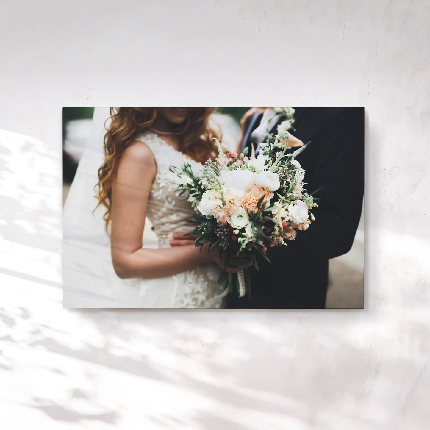 Canvas print featuring a close-up of a bride and groom holding a floral bouquet, with lace wedding dress details and soft outdoor lighting.