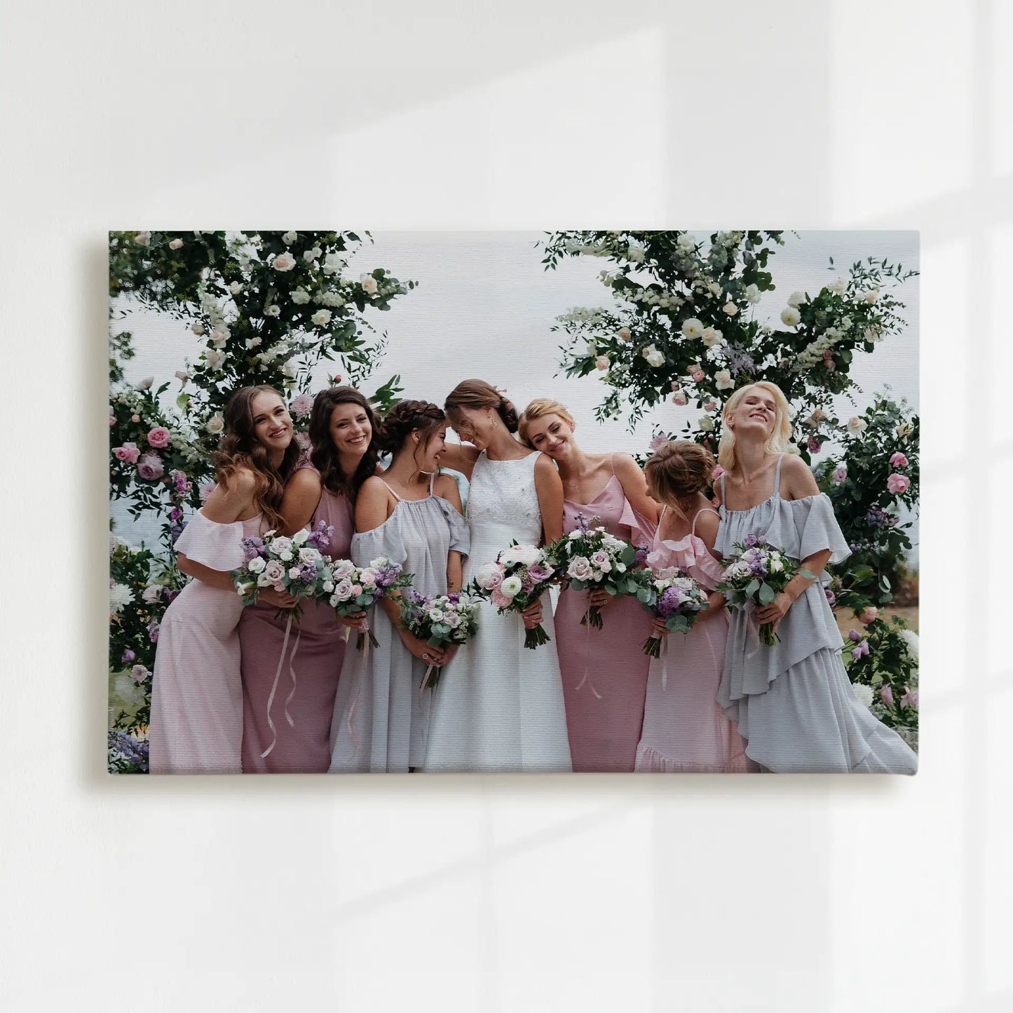 Canvas print showing a bride with six bridesmaids holding bouquets, standing beneath floral arches in an outdoor wedding setting.