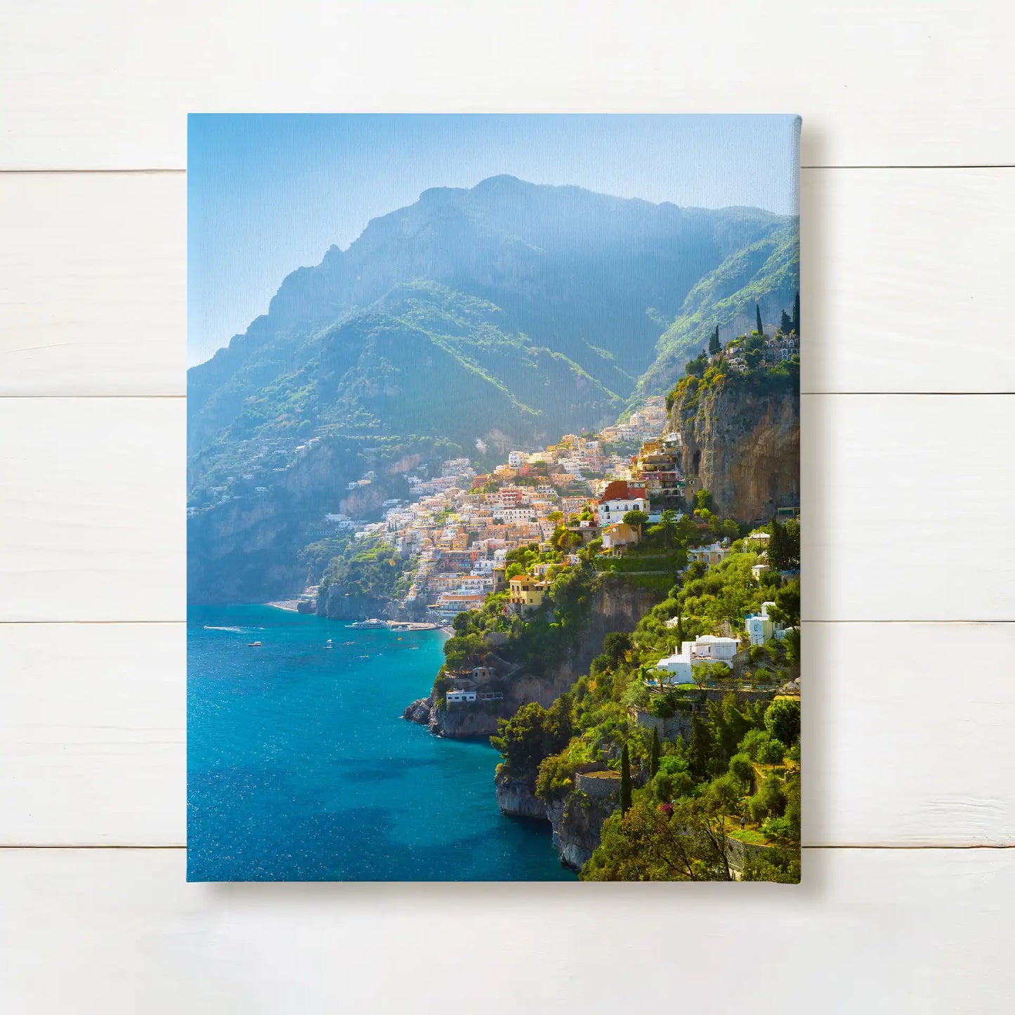Canvas print featuring a coastal hillside town with colorful buildings overlooking blue water and mountains in the background.