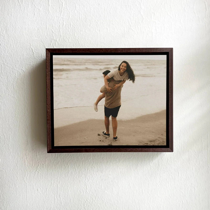 Framed canvas print on a wall featuring a couple sharing a joyful moment on the beach.