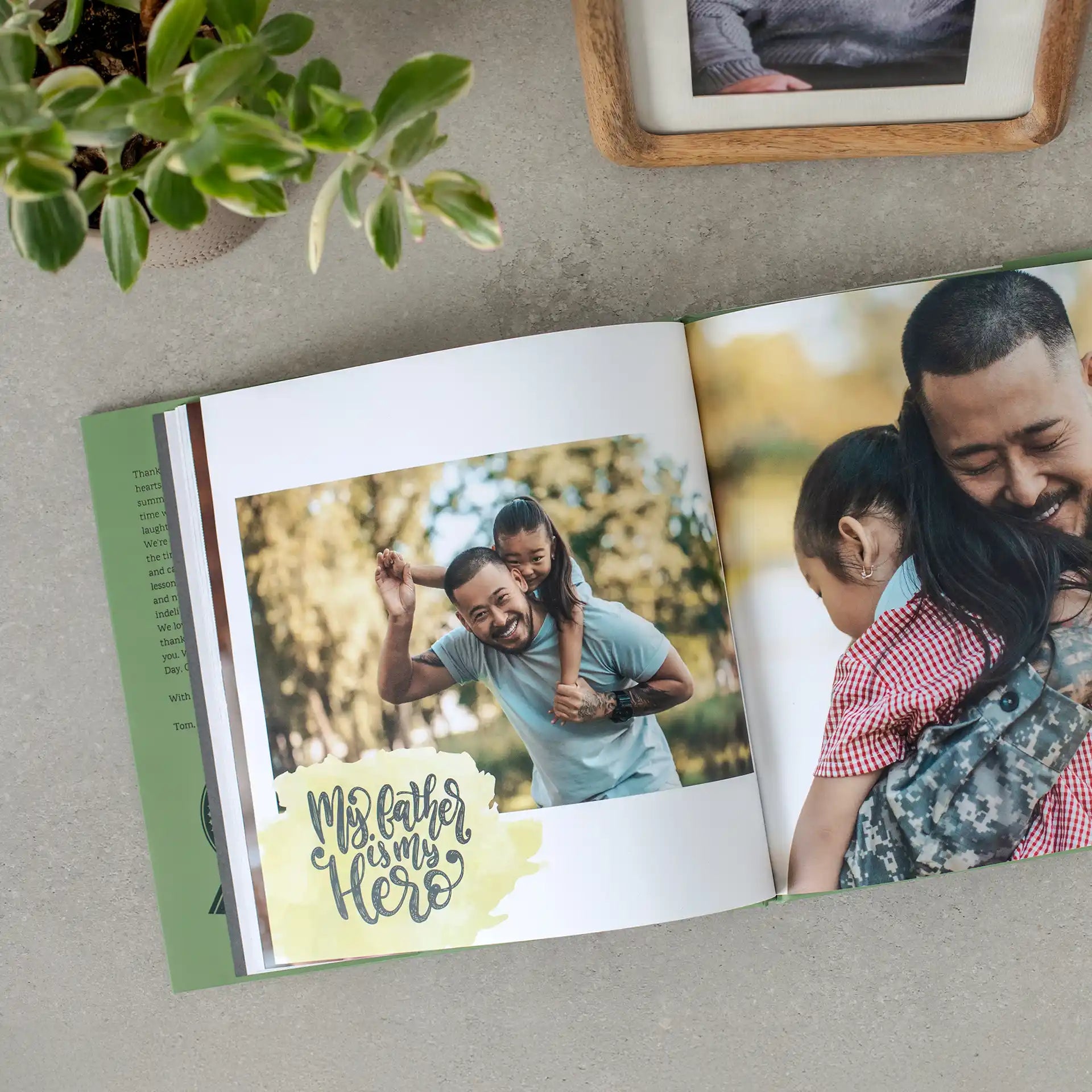 Open hardcover photo book showing a father and daughter laughing outdoors, with a military homecoming photo and "My father is my hero" quote on the pages.