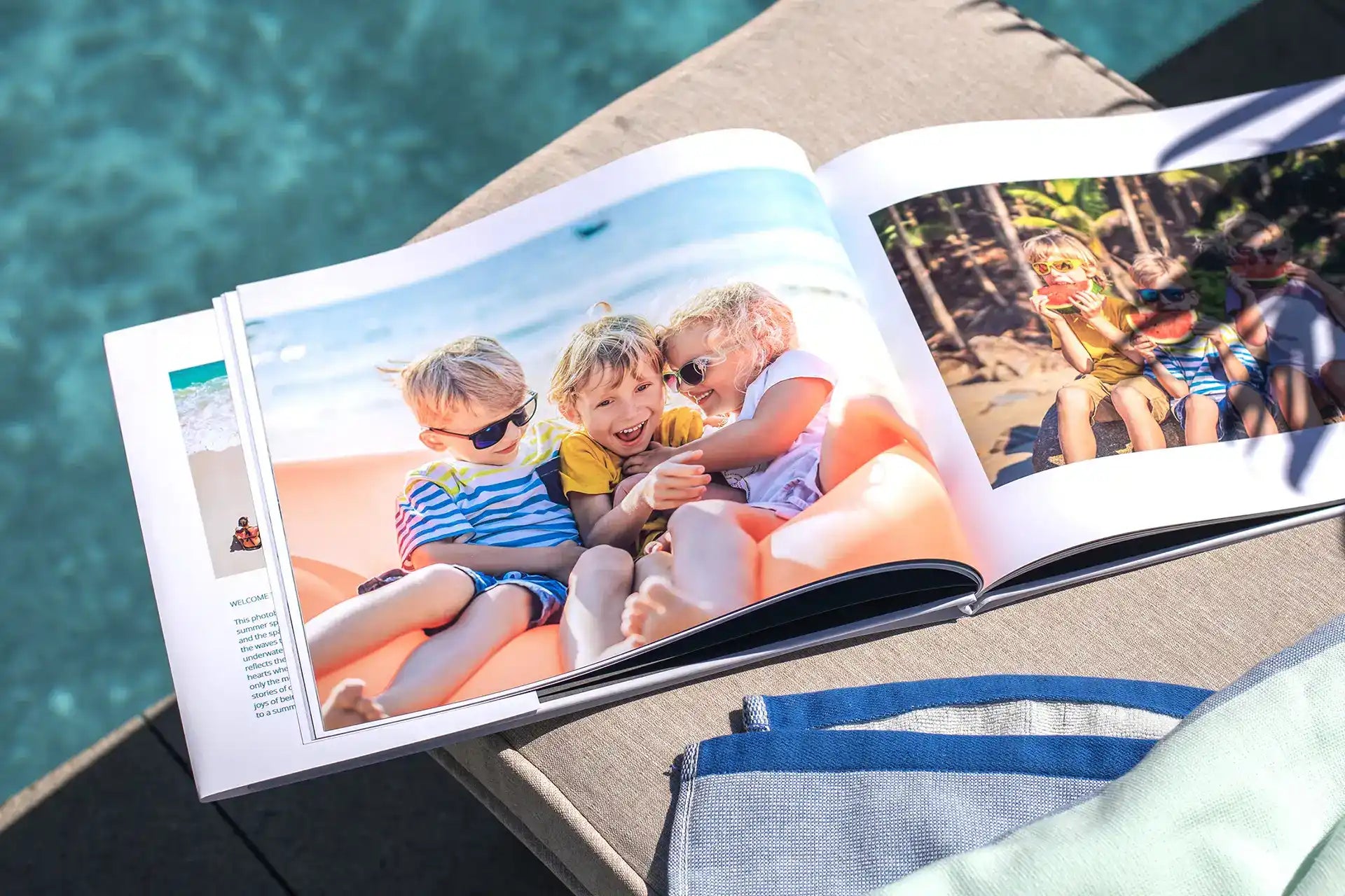 Hardcover photo book open to a beach spread, featuring three kids laughing together on an inflatable float with a beach photo on the facing page