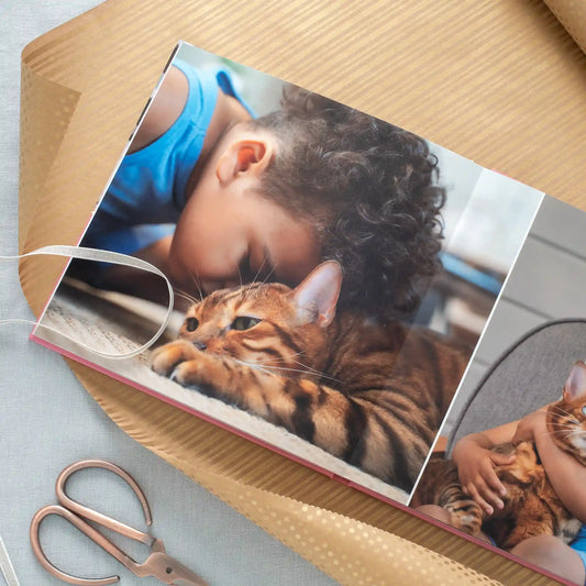 Layflat photo book open to a close-up photo of a curly-haired child nuzzling a striped tabby cat.