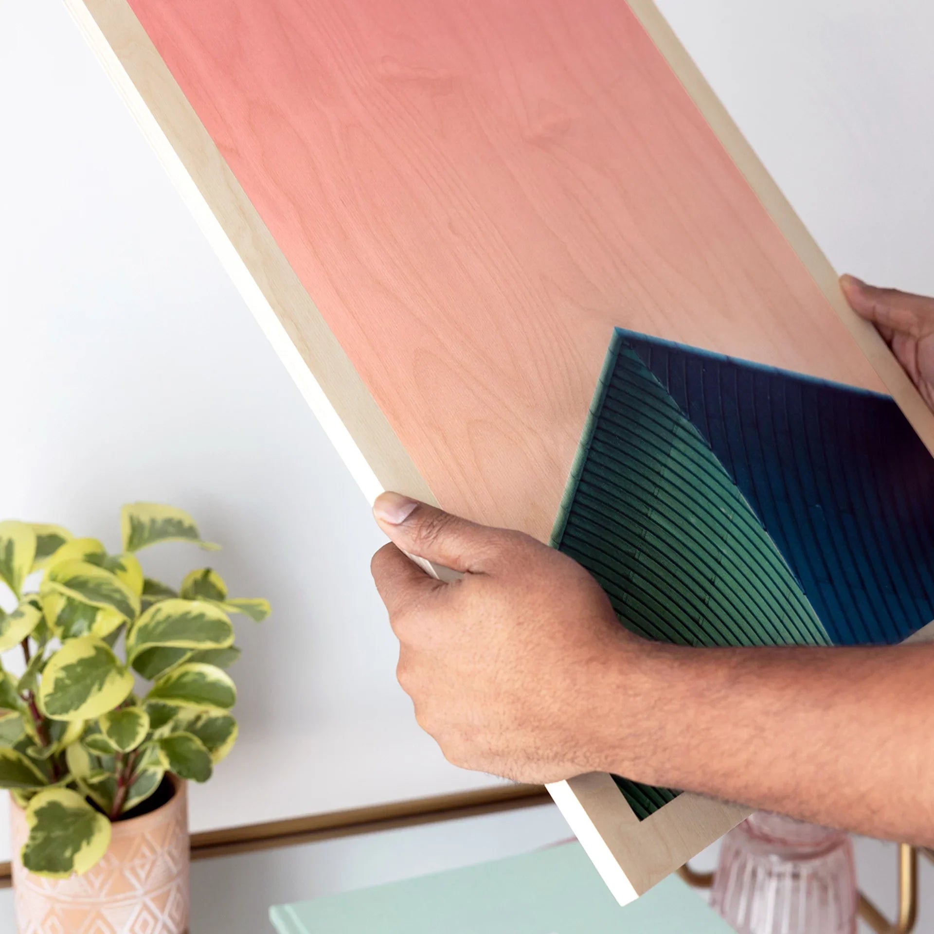 Maple wood print with abstract coral and teal geometric design, shown in hands to highlight natural wood grain and smooth panel edges.