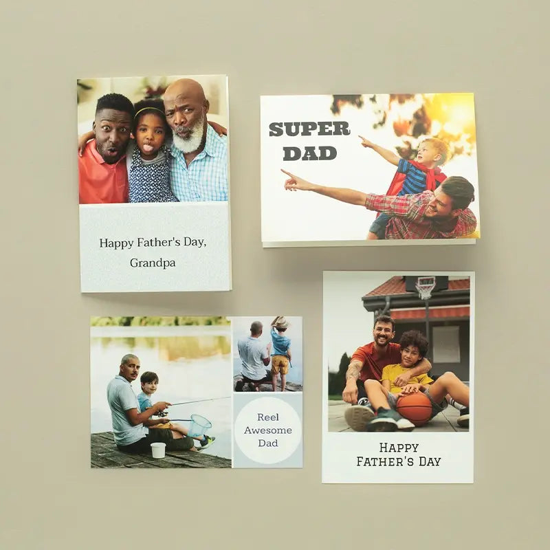 A collection of four custom Father's Day photo cards on a neutral surface, including a folded card reading 'Happy Father's Day, Grandpa,' a flat 'Super Dad' card, a fishing-themed 'Reel Awesome Dad' collage card, and a basketball-themed 'Happy Father's Day' flat card