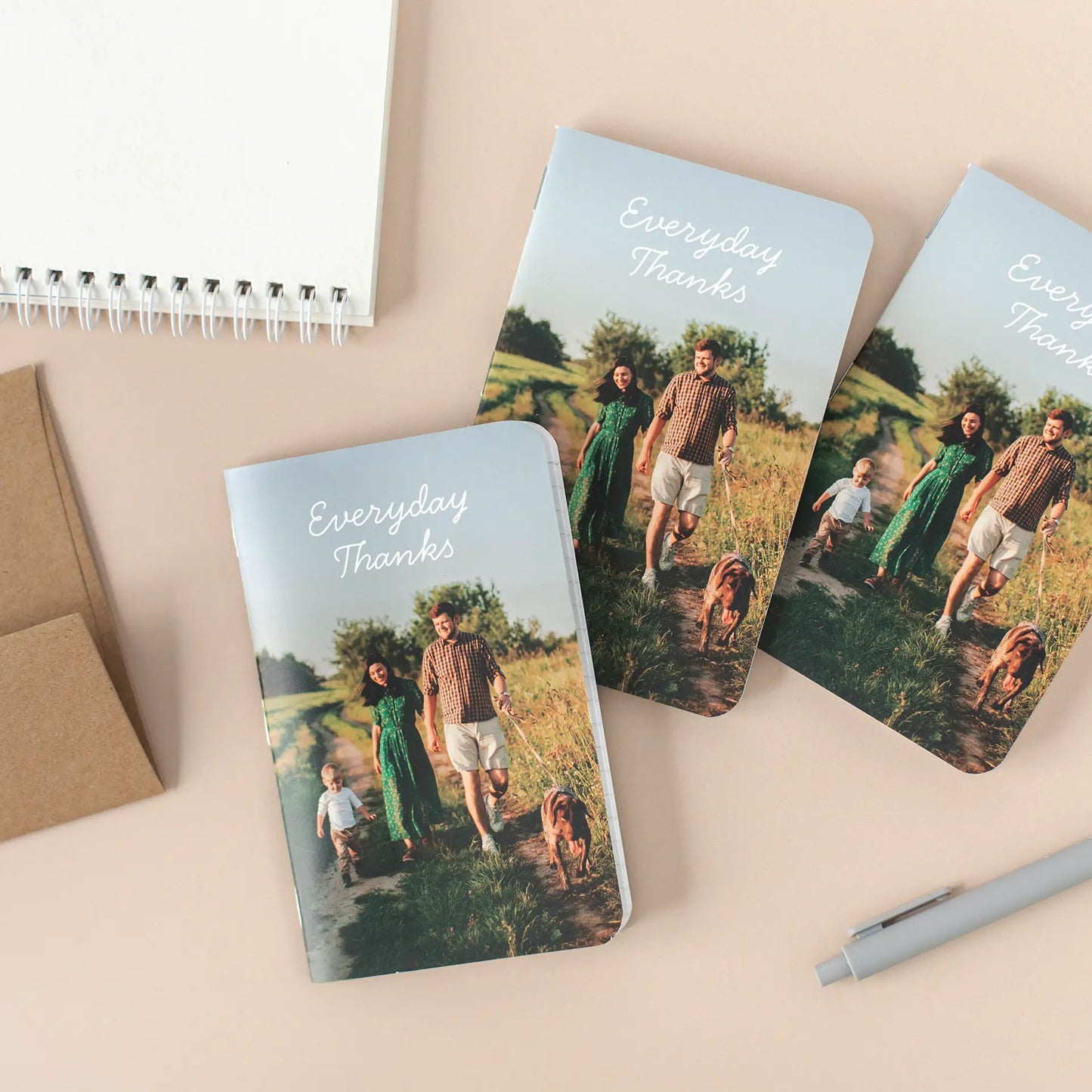 Three memo books with “Everyday Thanks” covers showing a family walking with a child and dog, arranged on a light background.