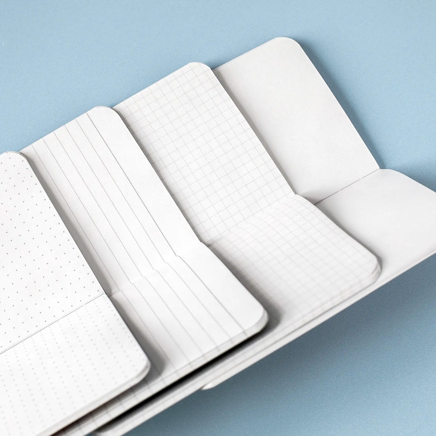 Open memo book showing multiple interior page styles, including dotted, lined, grid, and blank pages arranged side by side.