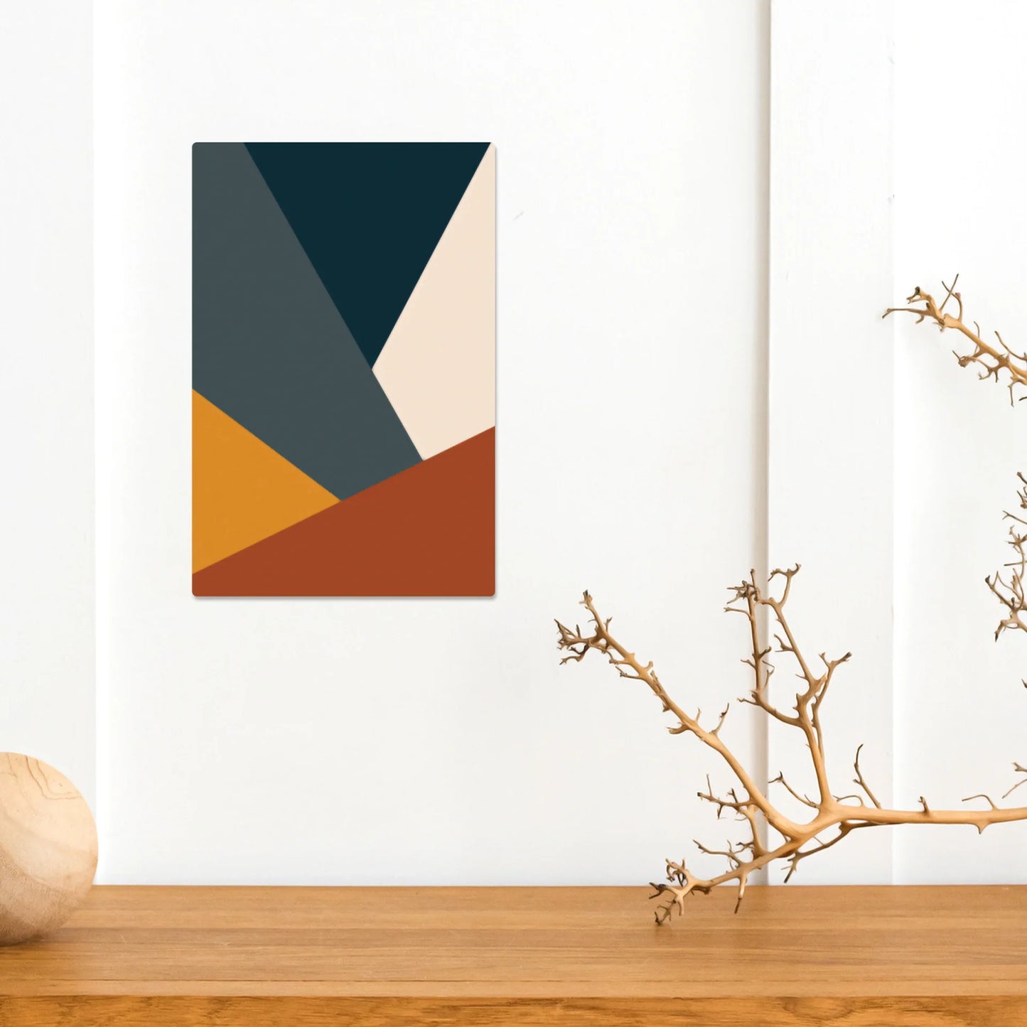 Metal wall print featuring abstract geometric color blocks in teal, mustard, rust, and cream tones, displayed above a wooden tabletop.