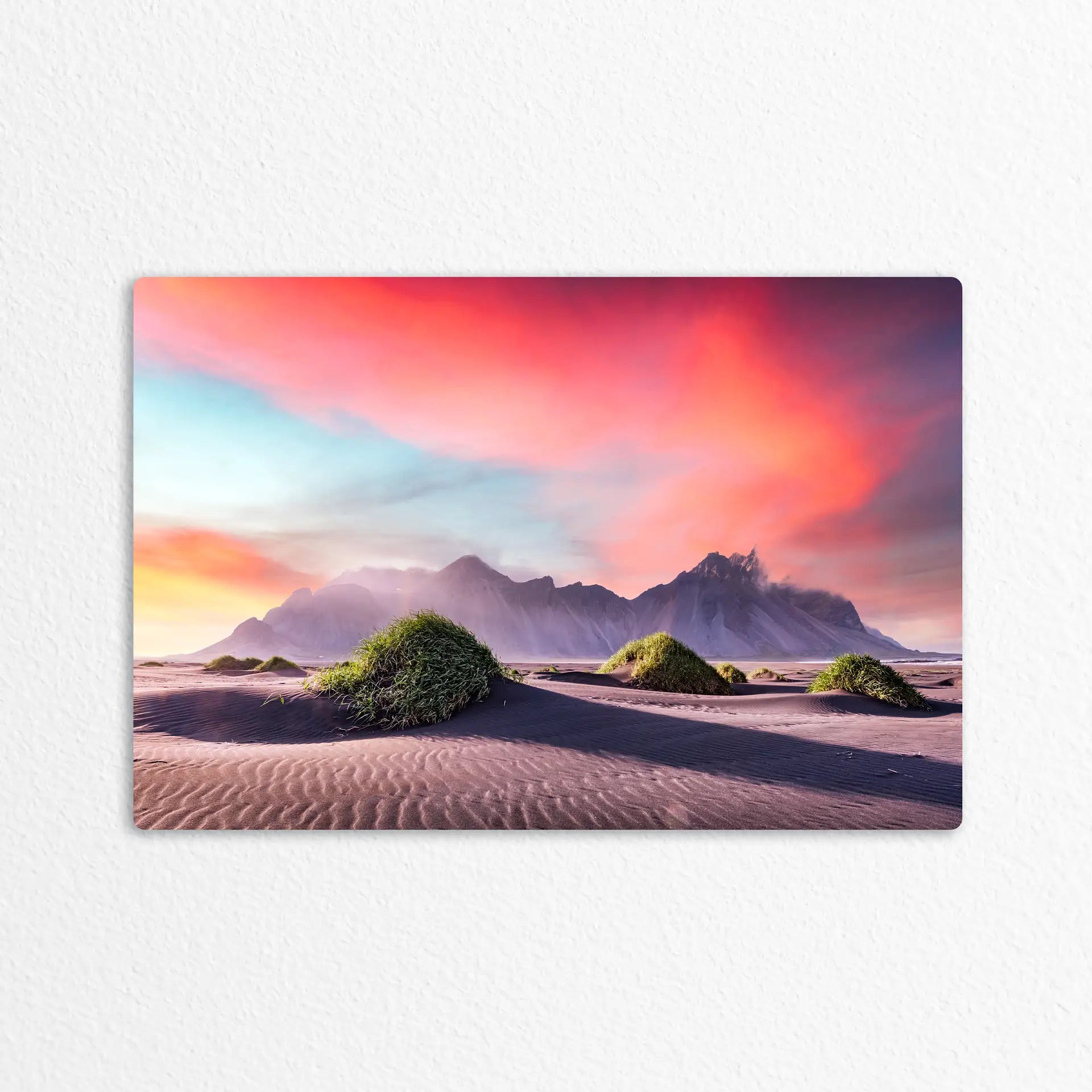 Metal wall decor print displaying colorful sand dunes with grassy mounds and distant mountains under a vibrant pink and orange sky.