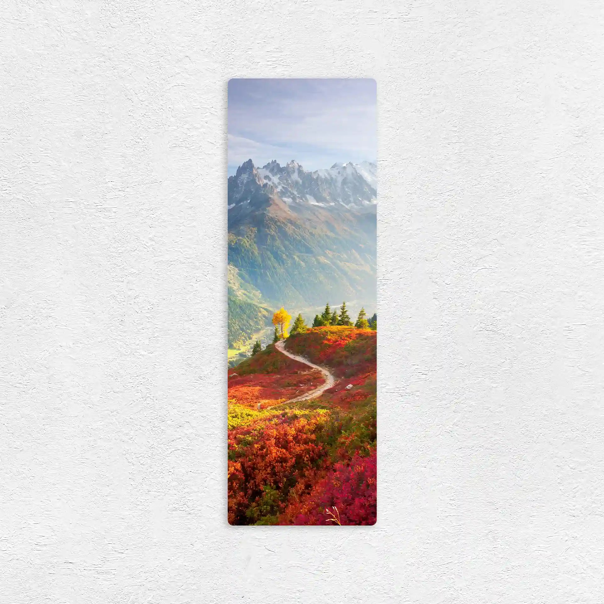 Vertical metal wall decor print of a winding path through bright red and green foliage leading toward a mountain range with snow-capped peaks.