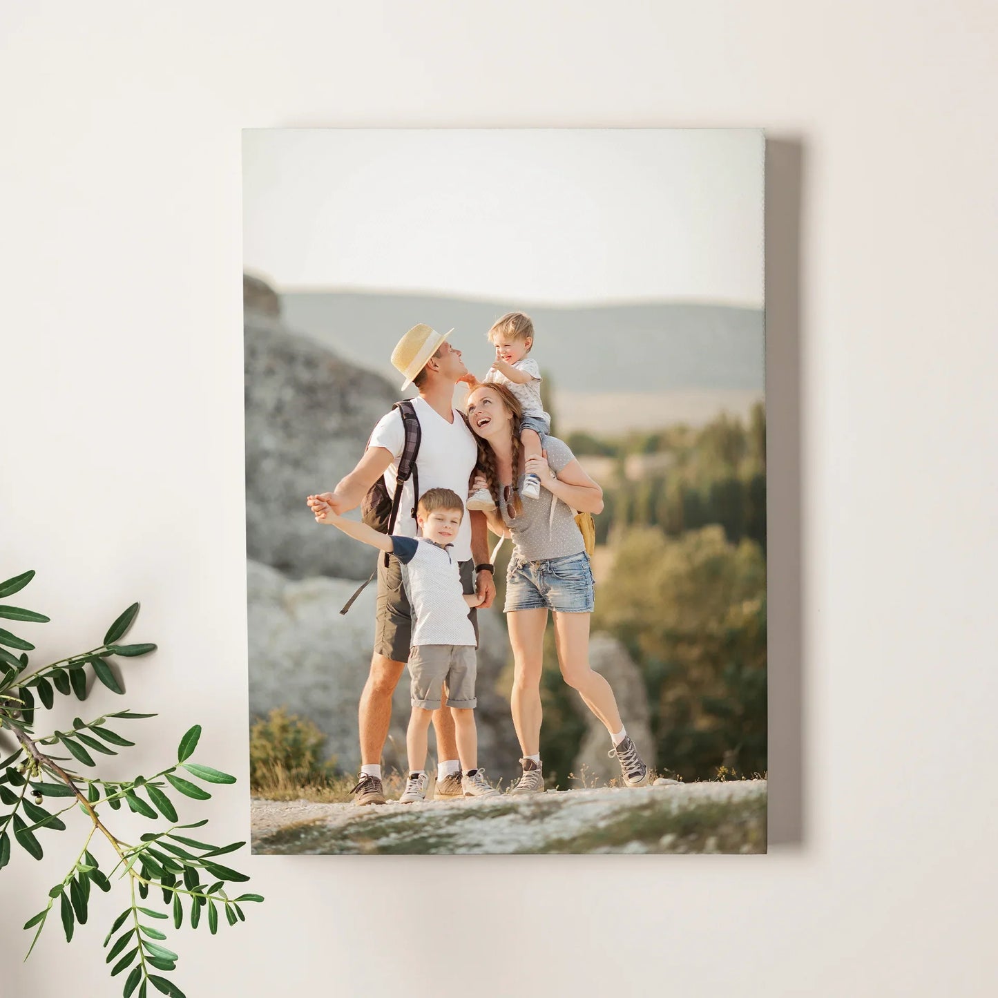 Mounted photo print showing a family with two children standing on a mountain trail, displayed on a neutral interior wall.