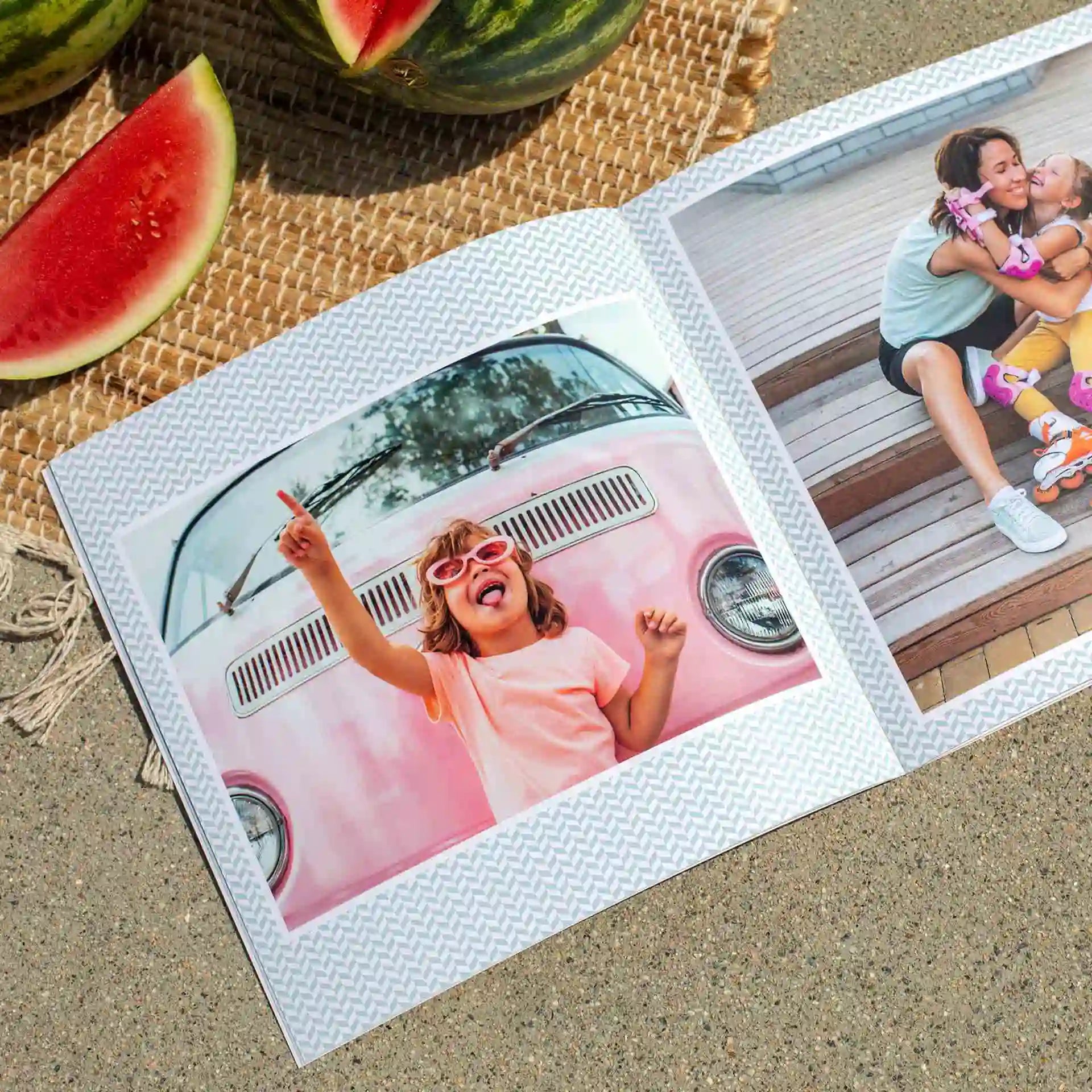Softcover photo book open to playful collage layout featuring child in sunglasses and parent-child moment, set on sand with watermelon slices.