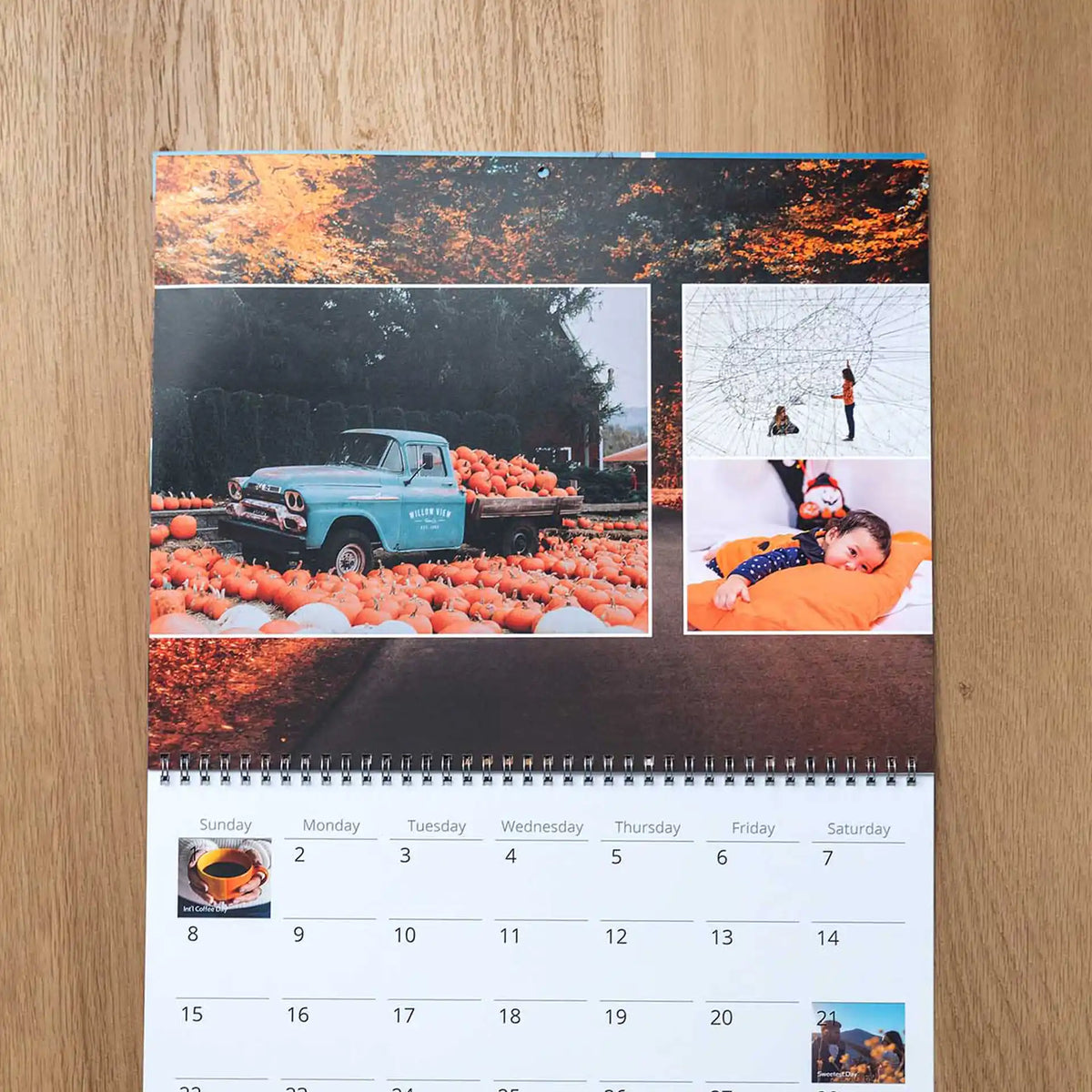 October wall calendar page with photos of a vintage truck full of pumpkins, a baby in fall pajamas, and a snowy art sculpture, above the date grid.