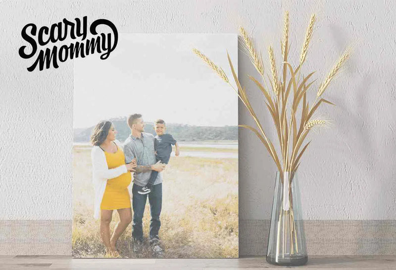 Scary Mommy logo above a canvas wall art print of a family standing in a grassy field beside a glass vase with dried wheat stems.