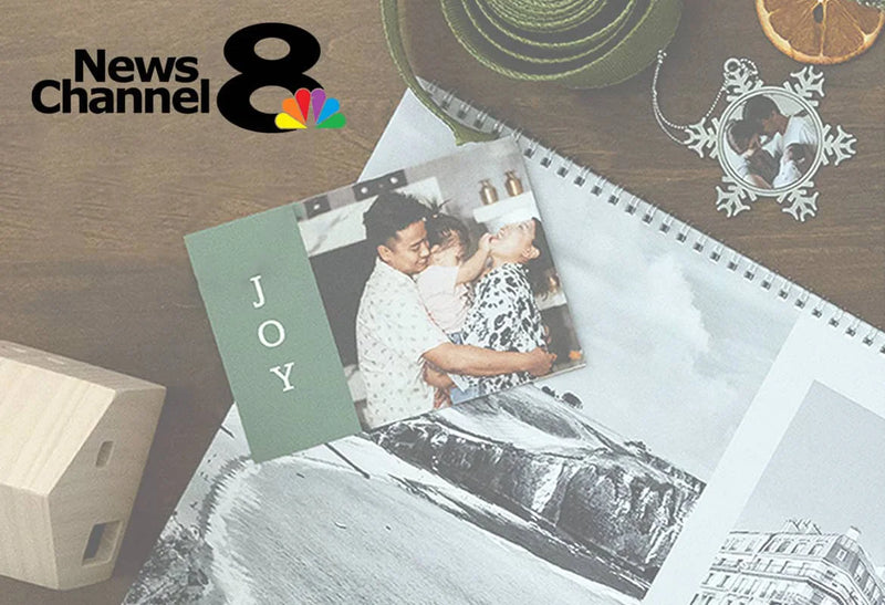 Flat lay of a custom photo calendar with a family photo card with the word “JOY,” alongside an ornament photo frame, and dried orange slices on a wooden table, with the News Channel 8 logo.
