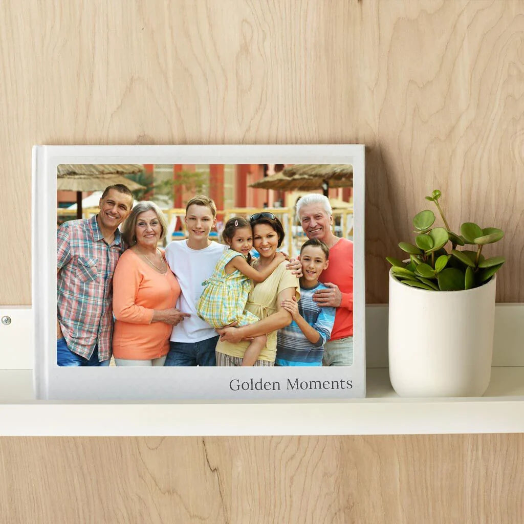 Hardcover photo book titled “Golden Moments” displayed on a shelf, featuring a smiling multigenerational family portrait on the cover.