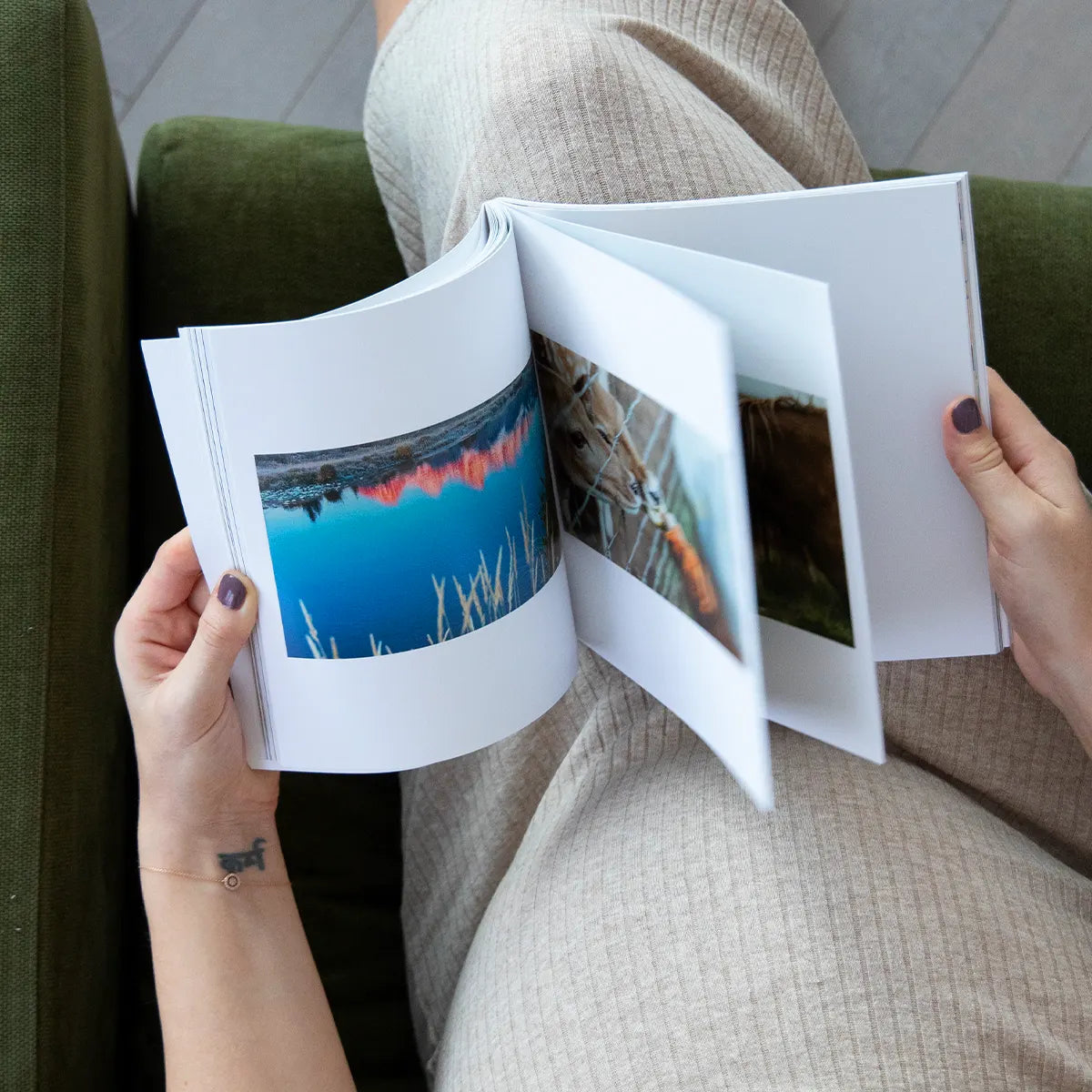 Person flipping through a softcover photo book featuring landscape and animal photographs printed on smooth white pages.