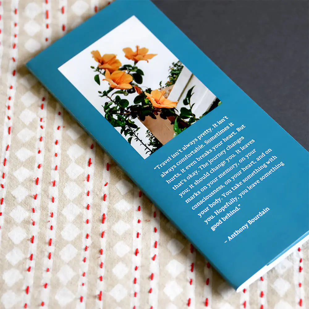 Hardcover photo book with a blue cover, featuring a centered photo and white text layout, placed on patterned fabric surface.