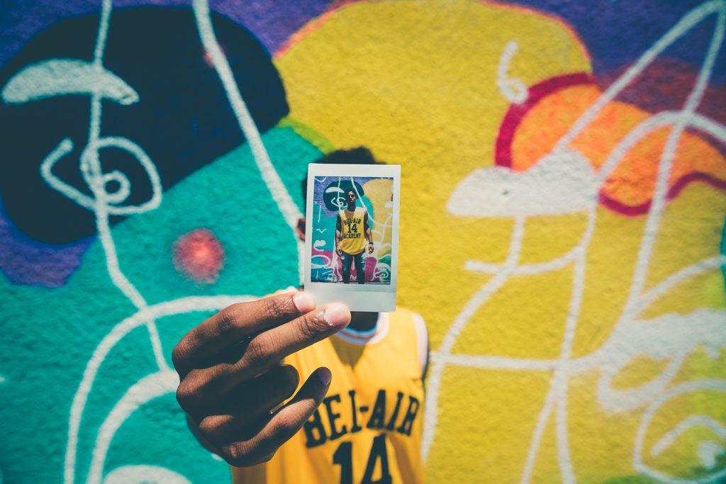 man squatting and taking picture with fuji instax camera wide 300