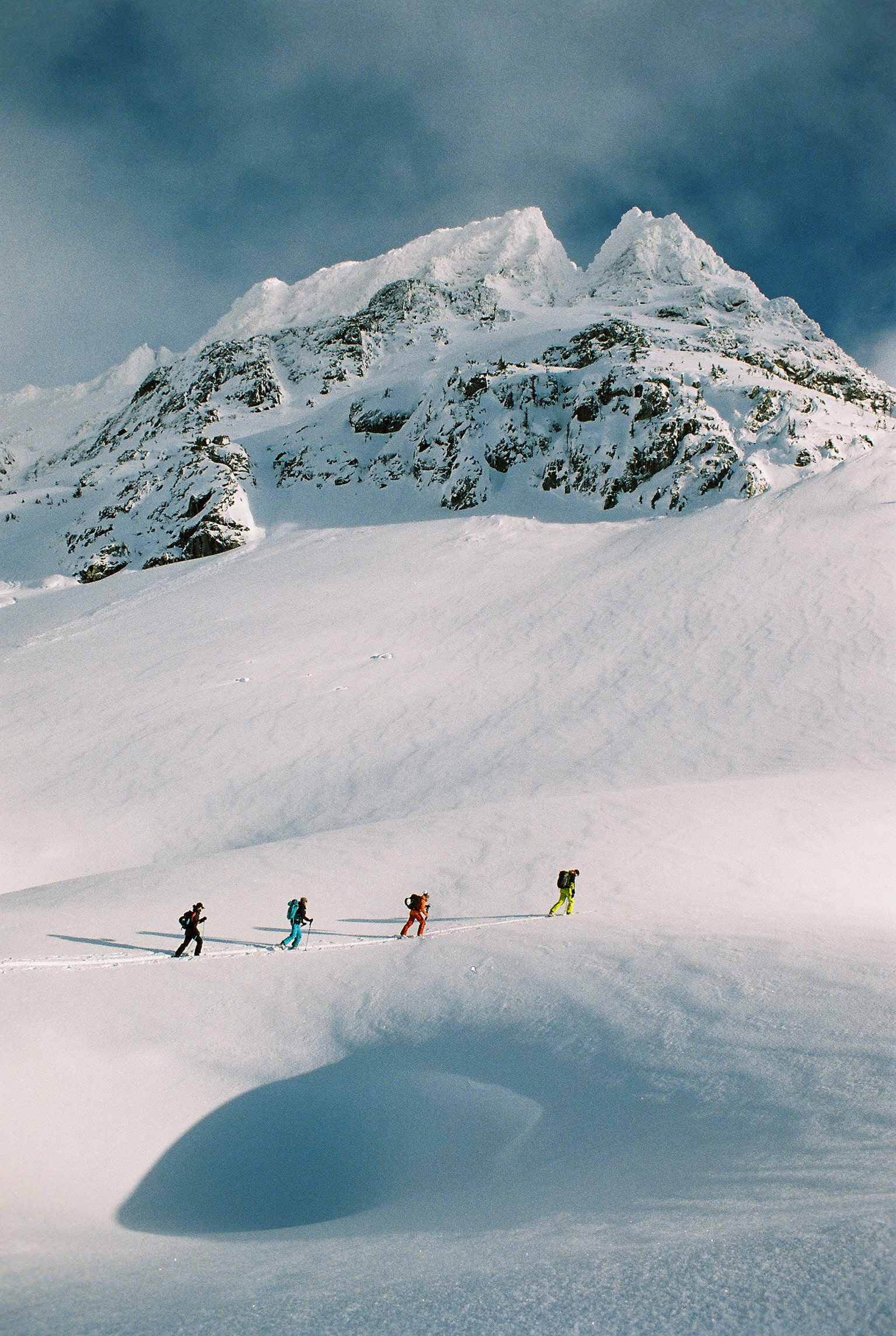 4 hikers walking across snowy landscape