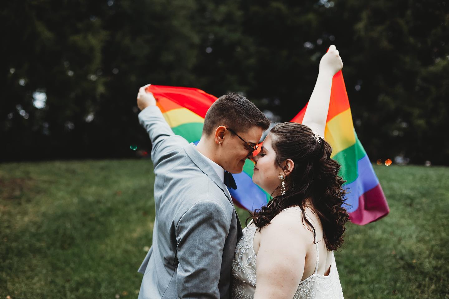 lgbtq+ couple holding rainbow flag in wedding photo
