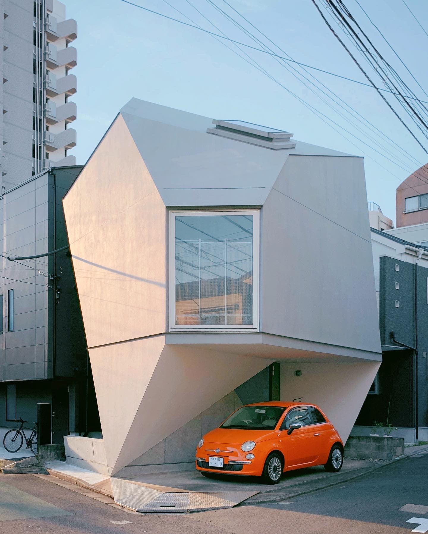 orange car parked in front of cool geometric building