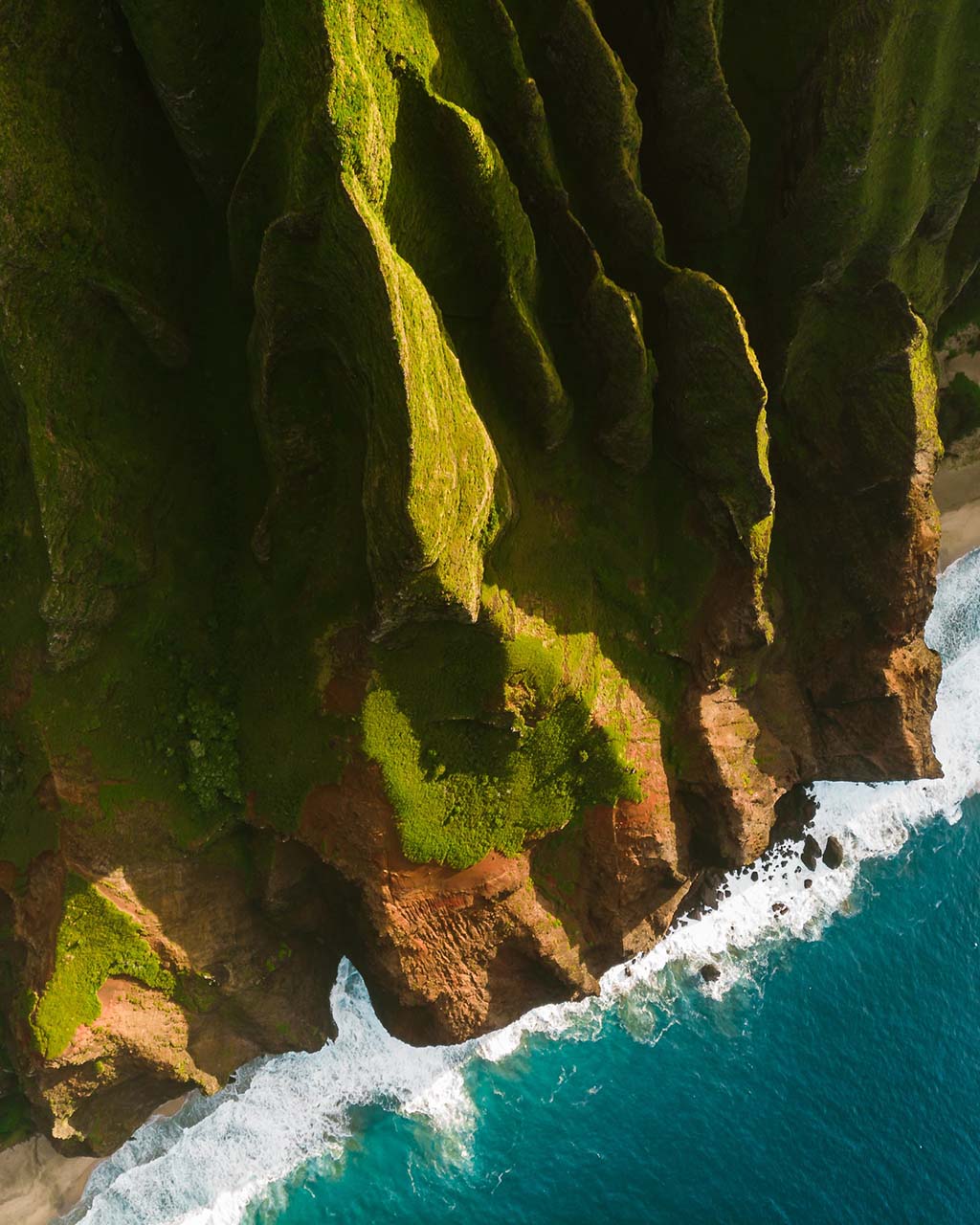 landscape shot of the edge of a green mountain by the water