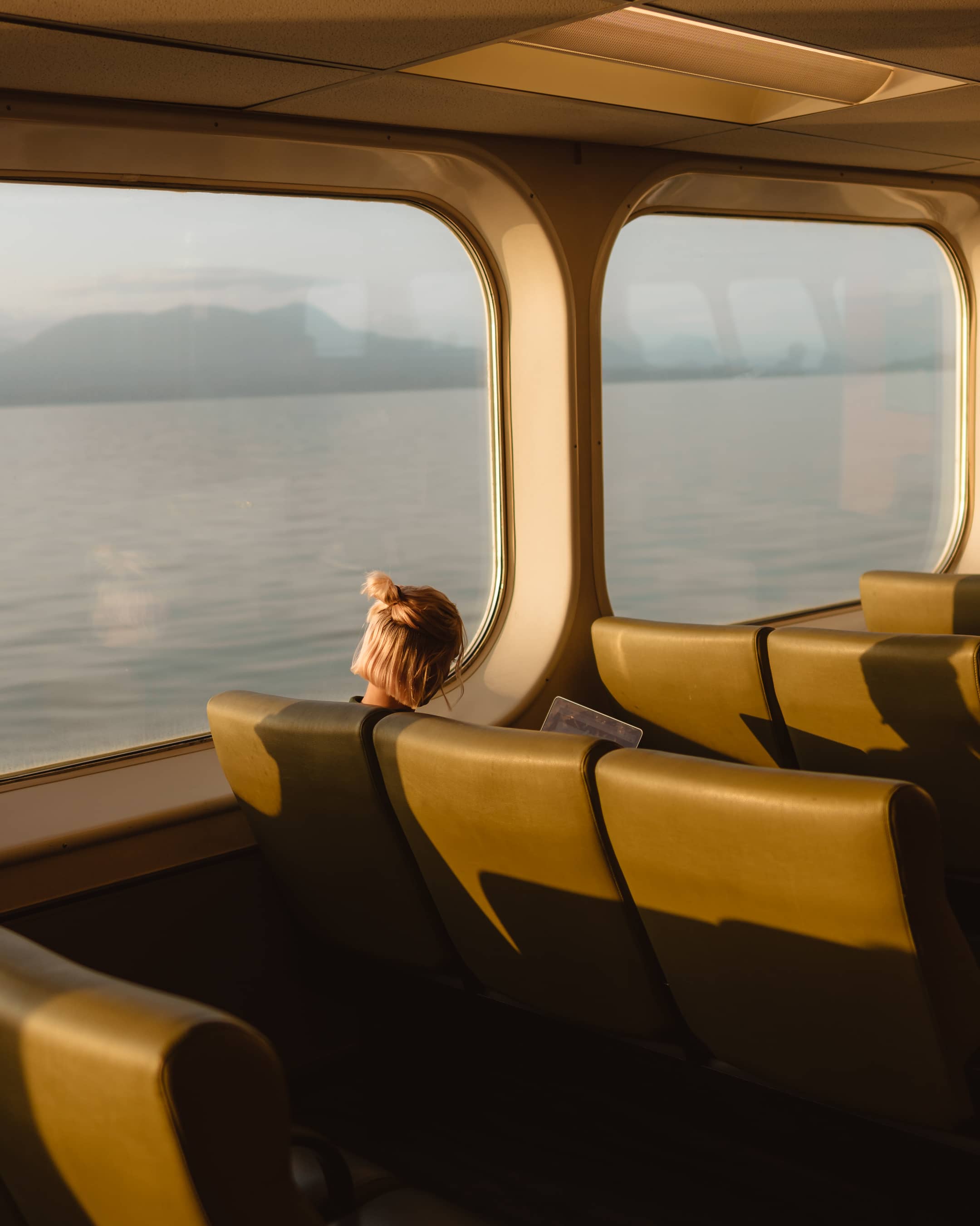 blonde girl sitting on a ferry looking out the window