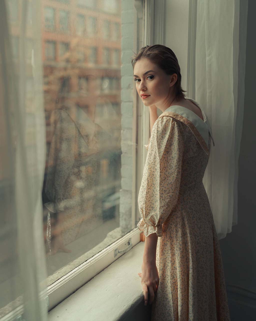 girl in a dress looking out the window