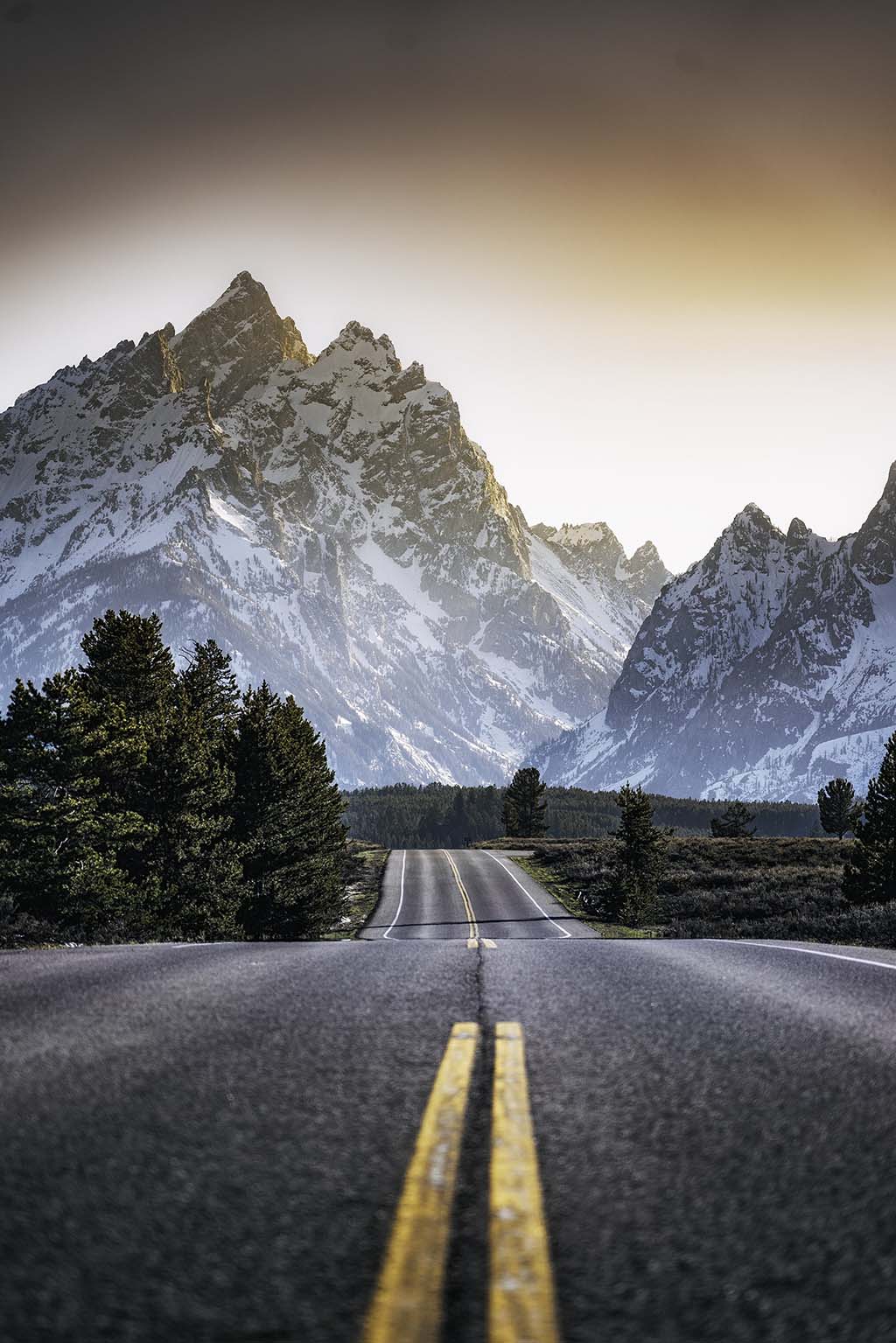 Shot from the middle of the road leading to a snowy mountain