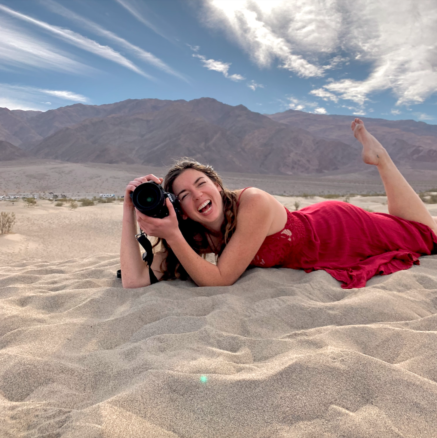 Girl laying in sand with large camera