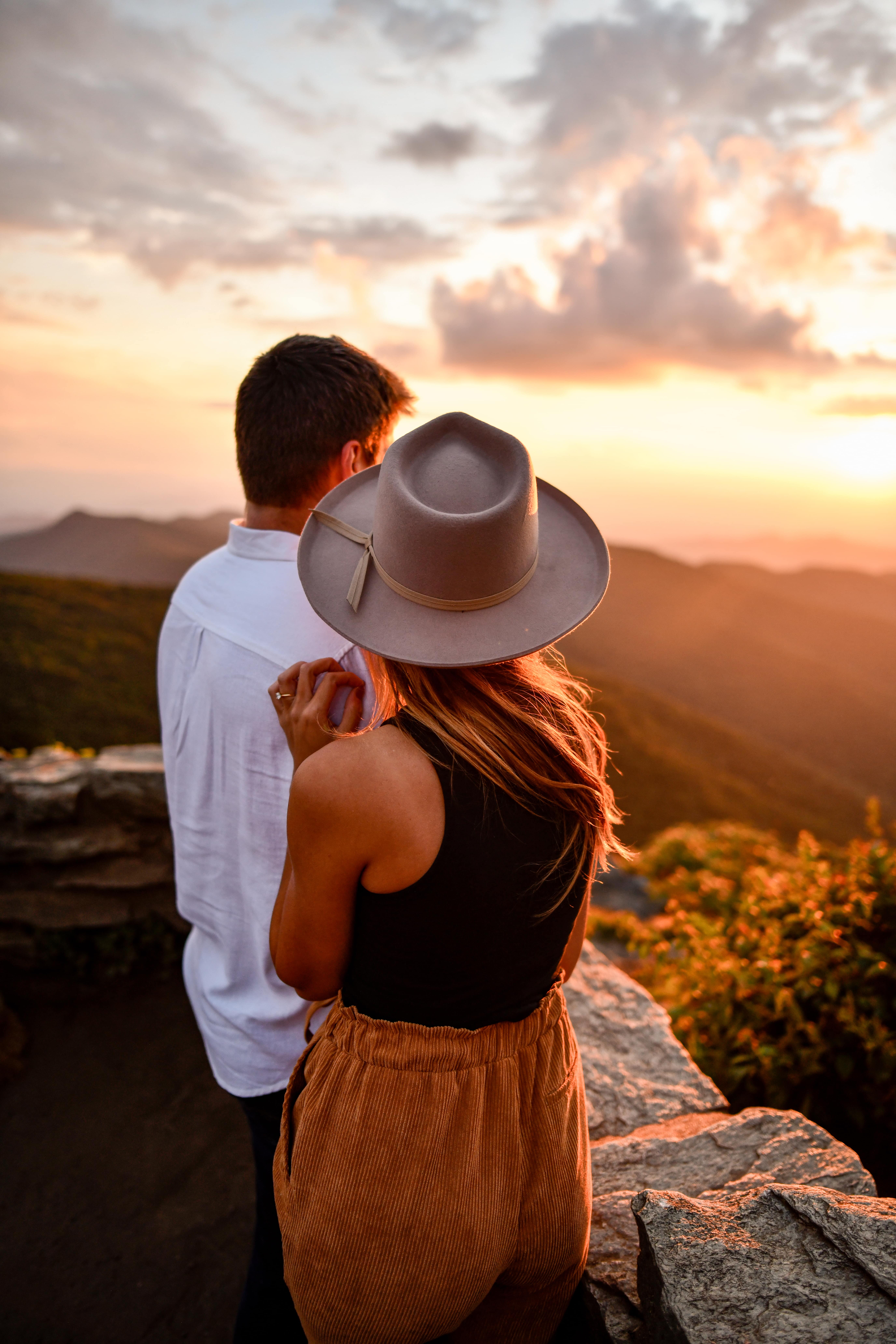 man and woman watching a sunset over the mountains