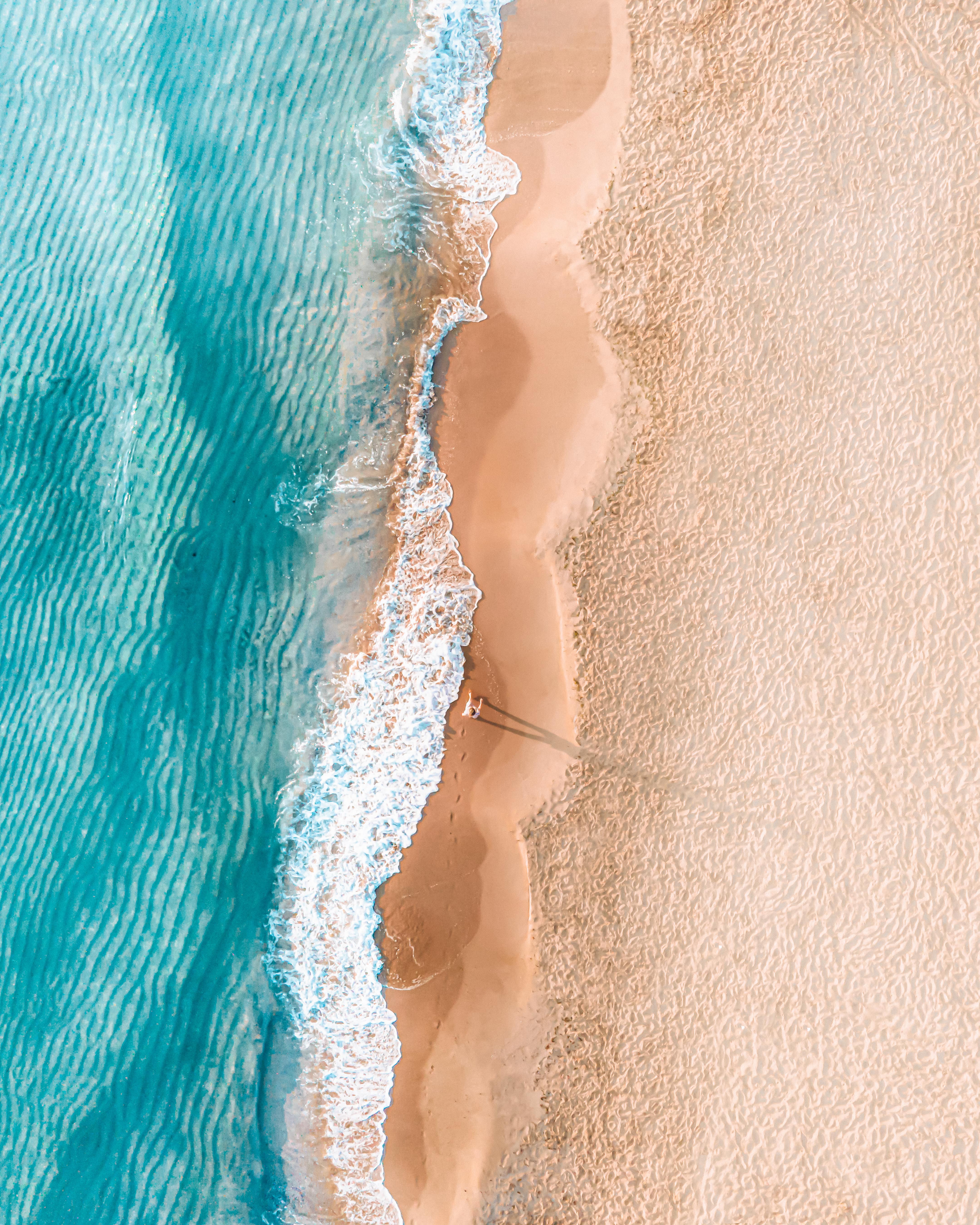 bright top down image of sand, waves and the ocean