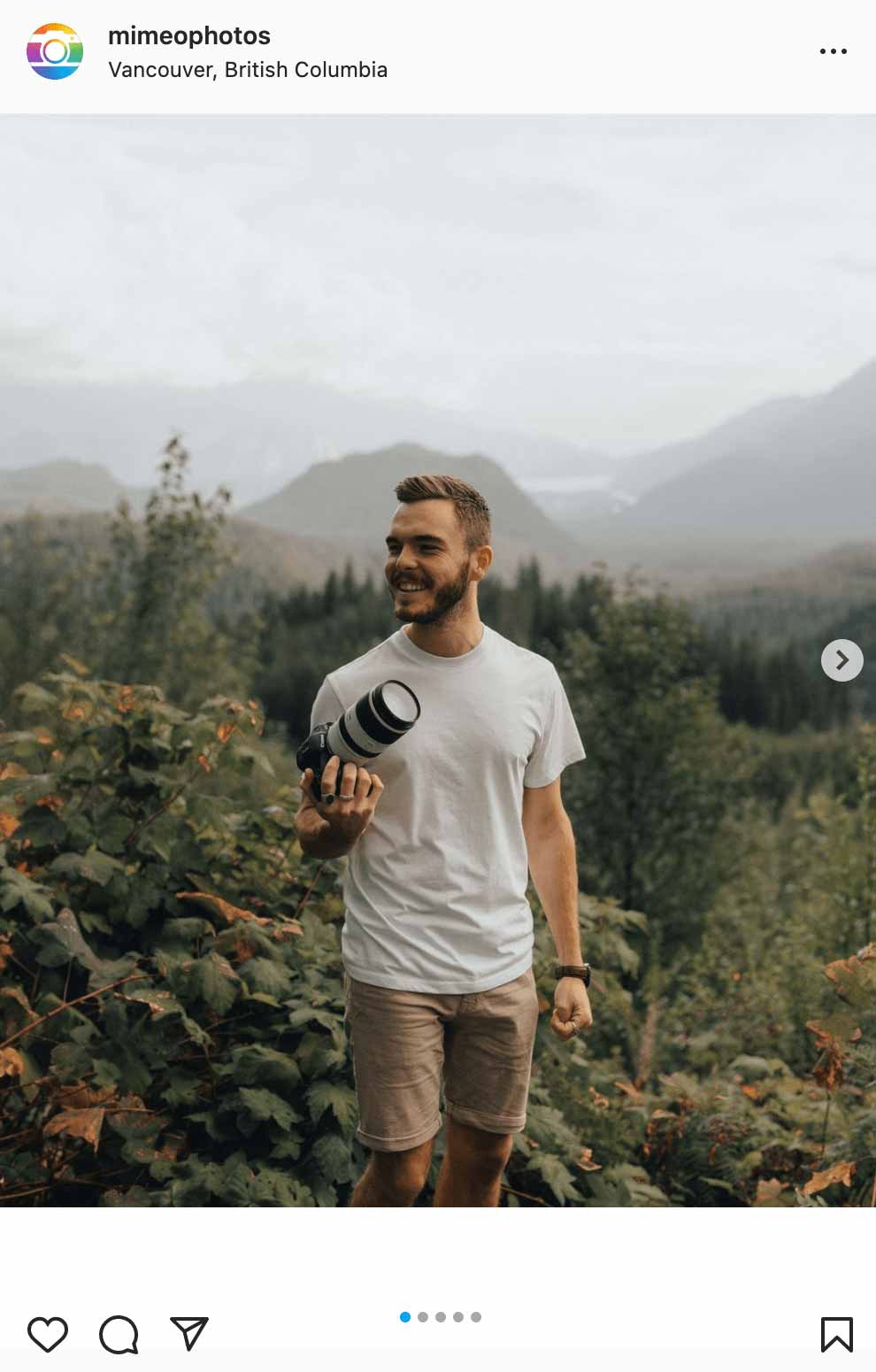 man holding camera with mountains in the back