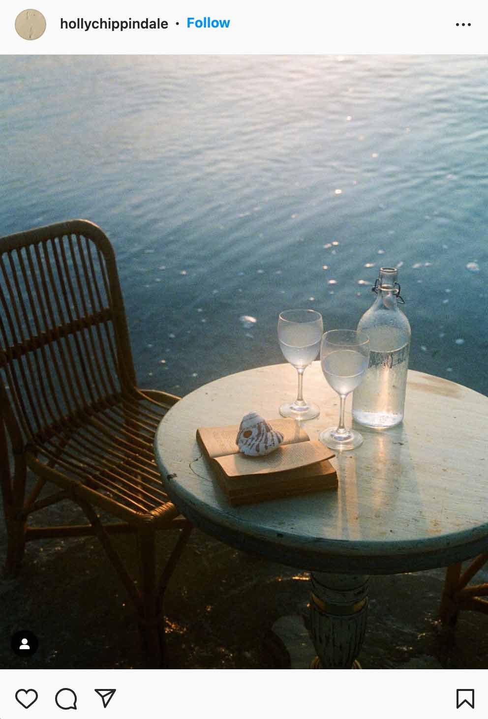 two wine glasses with water on table by the sea